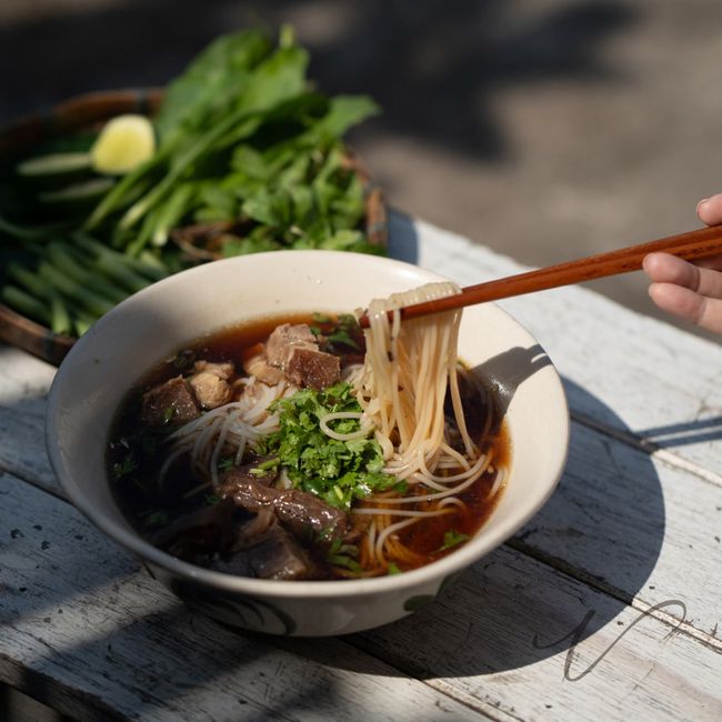 A savory Asian noodle soup bowl garnished with fresh greens, perfect for food photography.