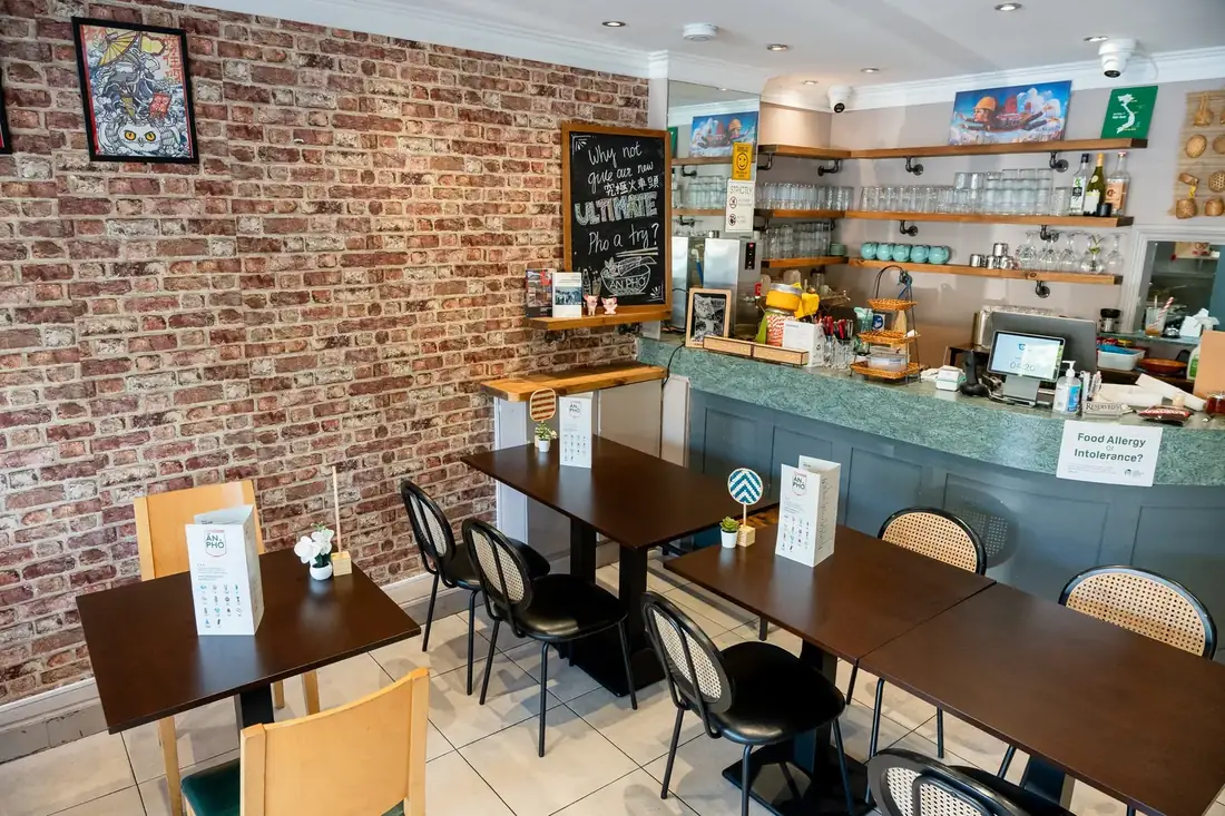 Inside Ăn Phở: wooden tables, brick wall and the counter